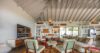Elegant living room at Villa Jocapana with vaulted ceilings, custom shelving, neutral sectional sofa, and sliding doors opening to the terrace.