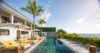 Infinity pool at Villa Jocapana lined with yellow-striped sun loungers and palm trees, overlooking the Caribbean Sea under a clear blue sky.
