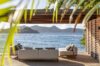 Seaside terrace lounge at a St Barts villa with modern sofas under a shaded pergola overlooking the ocean.