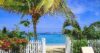 Beachfront St Barts villa with white picket gate opening to golden sand, turquoise sea, and views of offshore islands.
