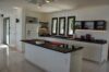 Spacious kitchen in a St Barts villa with black countertops, central island, and modern appliances under bright natural light.