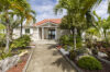 Pathway lined with tropical palms leading to a private villa with red roof and garden entrance in St Barts.