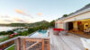 Luxury St Barts villa terrace with infinity pool, red lounge chairs, and panoramic ocean views at sunset.