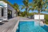 Sunny poolside deck at a St Barts villa with turquoise water, palm trees, and modern outdoor lounge area.