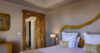 Elegant bedroom in a St Barts villa with carved wooden door, neutral tones, and artistic natural wood décor..