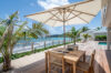 Alfresco dining table under a parasol at a beachfront St Barts villa with ocean views