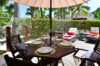 Outdoor dining table under an umbrella with sun loungers in a tropical garden at a St Barts villa rental