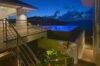 Evening view of an illuminated infinity pool at a St Barts villa, with hillside lights and ocean horizon in the background.