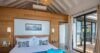 Inviting bedroom in a St Barts villa with wooden accent wall, vaulted ceiling, and sliding doors opening to the terrace.