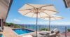Sunlit pool terrace at a St Barts villa with loungers, parasols, and panoramic Caribbean Sea views from a wooden deck.