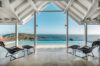 Open-air lounge with sun chairs facing an infinity pool and sweeping Caribbean Sea views in a St Barts villa.