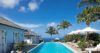 Long infinity pool lined with sun loungers and palm trees at luxury St Barts villa rental.