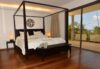 Spacious bedroom with four-poster bed, wooden floors, and balcony access in St Barts villa rental