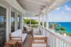 Covered terrace at St Barts villa with white lounge seating and views of turquoise sea