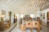 Open-plan villa interior with wooden dining table, loft-style ceiling, and bright living area in St Barts