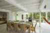 Covered outdoor dining area with wicker chairs, set table, hammock, and garden views at a villa in St Barts.