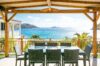 Covered outdoor dining terrace with wicker table and chairs overlooking Flamands Bay at St Barts villa rental