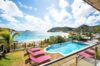 Infinity pool with pink loungers overlooking Flamands Bay and hillside homes, luxury St Barts villa rental