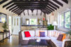 Cozy living room in a St Barts villa with vaulted beamed ceiling, rattan sofa, and open-plan kitchen.