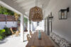 Shaded outdoor dining space at a St Barts villa, with woven lanterns, long wooden table, and tropical garden views