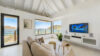 Bright living room with sofa, large windows framing ocean views, and modern décor in St Barts villa