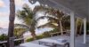 Oceanfront wooden deck with sunbeds, palm trees, and sea view at private villa in St Barts
