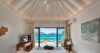Bedroom in St Barts villa with vaulted ceiling, balcony, and panoramic Caribbean Sea view.