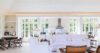 Spacious living room in St Barts villa with white sofas, open kitchen, and garden views.