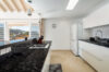 Modern villa kitchen with black granite countertops, white cabinets, and terrace view in St Barts villa rental.