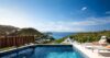 Villa infinity pool with sun loungers overlooking hills and turquoise ocean in St Barts luxury villa rental.