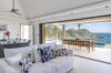 Bright villa living room with white sofa, open dining terrace, and ocean view pool in St Barts luxury vacation rental.
