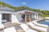 Contemporary villa with sun loungers, shaded dining terrace, and poolside deck in St Barts vacation rental.