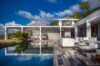 Modern St Barts villa with poolside deck, sleek white lounge seating, and shaded outdoor dining area beside the infinity pool.