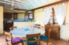 Cozy dining area at St Barts villa with round table, wooden chairs, and open kitchen