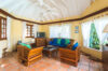 Bright living room at St Barts villa with wooden furniture, terracotta floors, and garden views