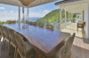 Spacious villa terrace with long wooden dining table, wicker chairs, and ocean views in St Barts luxury vacation rental.