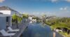 Infinity pool at a luxury St Barts villa with sun loungers, palm trees and panoramic hillside views