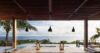 Covered terrace at a St Barts villa with lanterns, wooden deck, and infinity pool overlooking the ocean and lush hillsides.