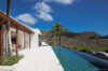 Sleek infinity pool at modern St Barts villa with mountain views and palm tree