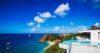 Oceanfront St Barts villa with infinity pool and terrace loungers overlooking a sandy cove, turquoise sea, and sailing yachts.