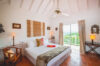 Charming villa bedroom with terracotta tile floors, double bed, and balcony view in St Barts vacation rental.