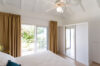Simple bedroom with sliding glass doors, ceiling fan, and terrace access at St Barts villa rental