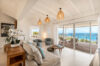 Coastal-style living room with rattan lights and ocean view terrace at St Barts villa rental