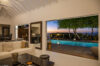 Evening view from a St Barts villa living room with white sofa, opening to a pool deck and ocean sunset