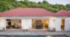 St Barts villa with red roof and open living spaces facing the pool deck, surrounded by tropical hillside greenery