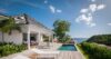 Private St Barts villa with ocean-view pool, sun loungers, and covered dining terrace surrounded by lush greenery and blue skies