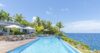Stunning view of a sparkling pool overlooking the vast ocean under a clear sky.