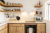 Rustic villa kitchen with wooden cabinets, open shelving, modern appliances, and bright window light in St Barts vacation rental
