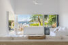 Bright villa living room with white décor opening to terrace and panoramic view of Gustavia harbor in St Barts rental