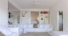 Minimalist villa living room with white sectional sofa, built-in shelving, and open doorway to bedroom in St Barts rental
